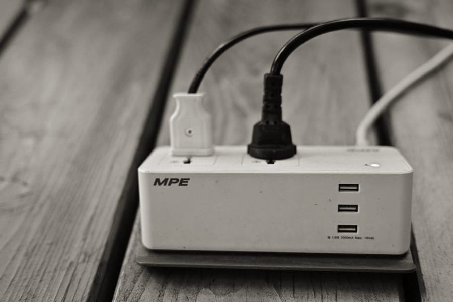 A universal travel plug adapter beside a charging cable