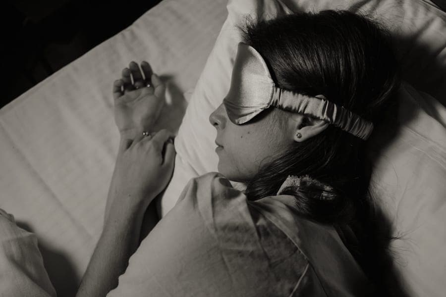 A traveler asleep on their side wearing an eye mask