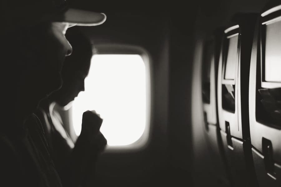 A passenger seated beside an aircraft window on a long flight