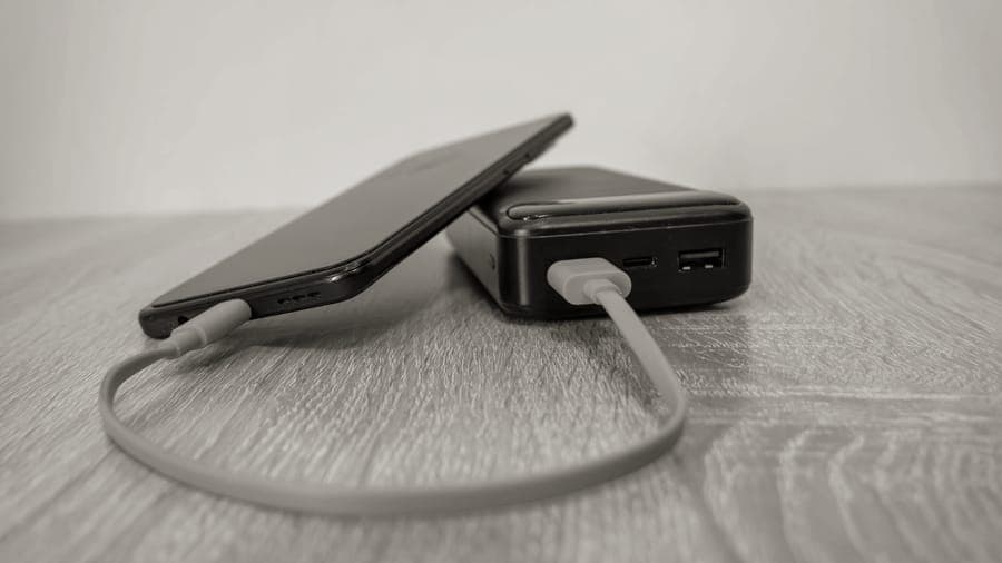 A portable power bank charging a phone on a table