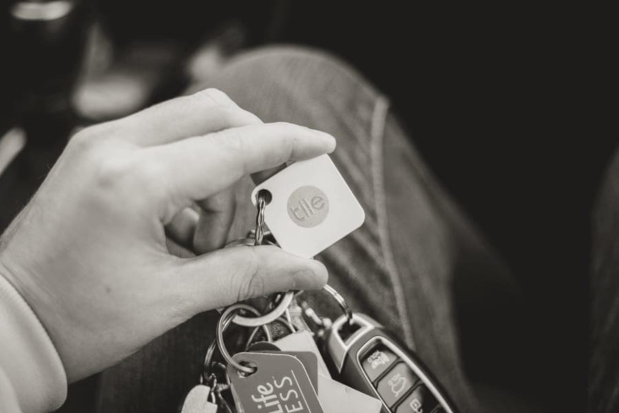 A small Bluetooth tracking device beside a packed travel bag