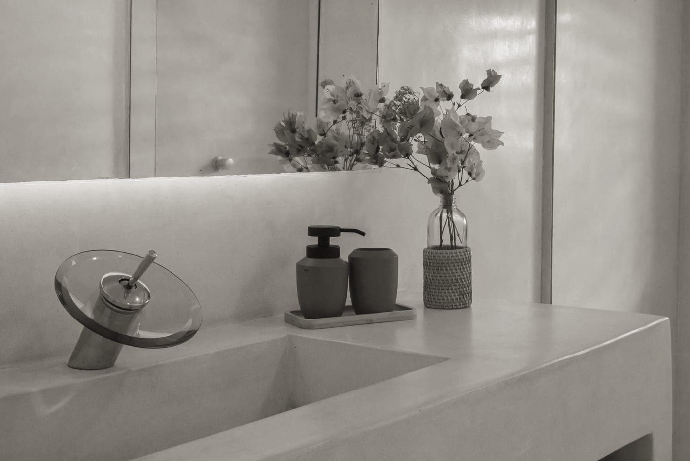 A hotel bathroom counter with a washbag and toiletries laid out beside the sink