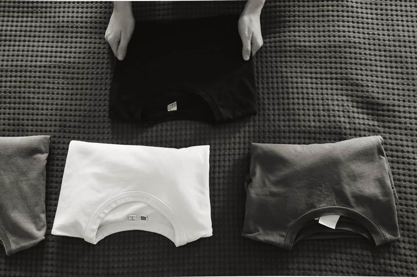 Neatly folded clothes stacked beside an open bag ready for packing