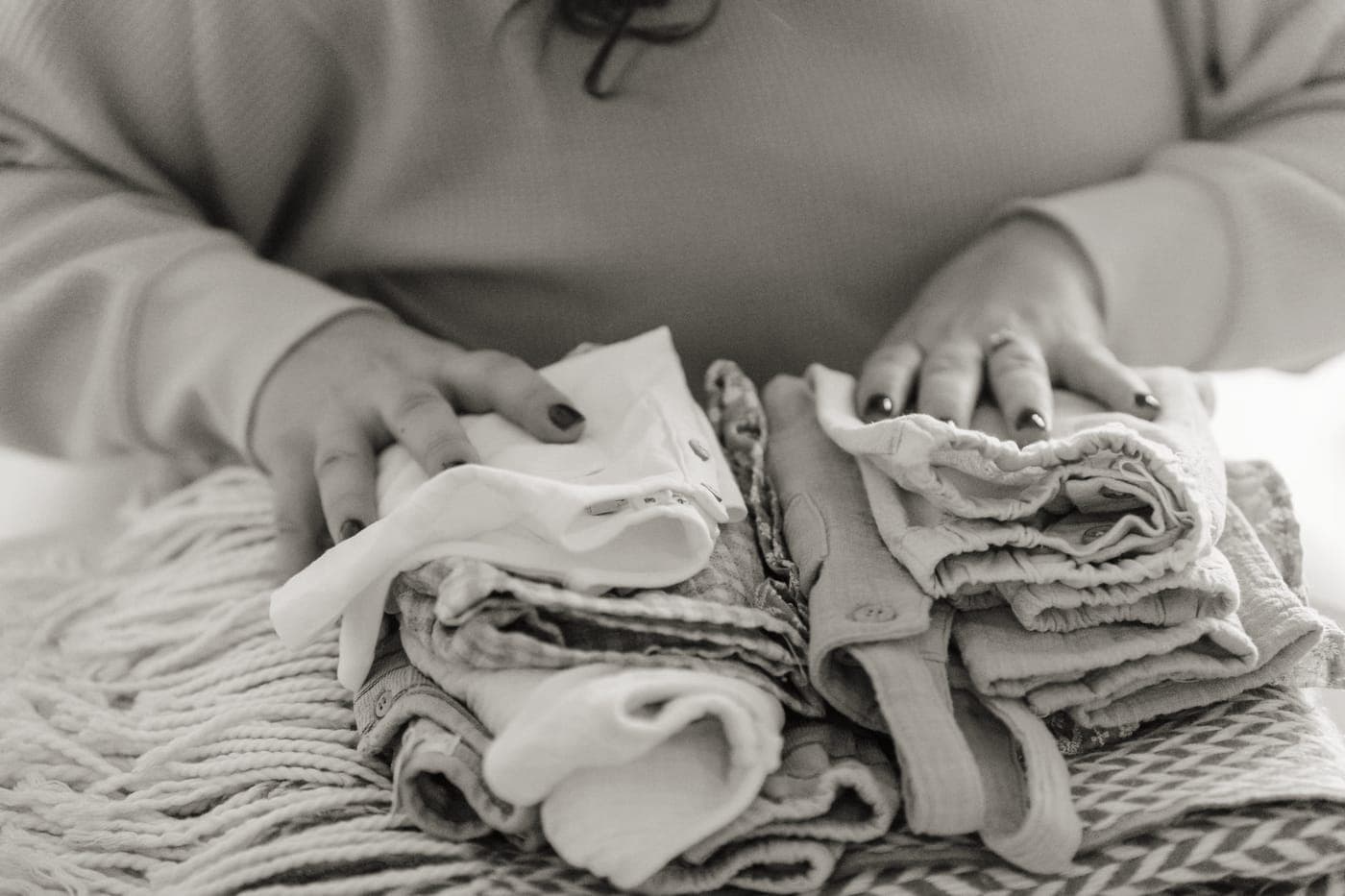 Clothes folded in stacks beside an open suitcase on a bed