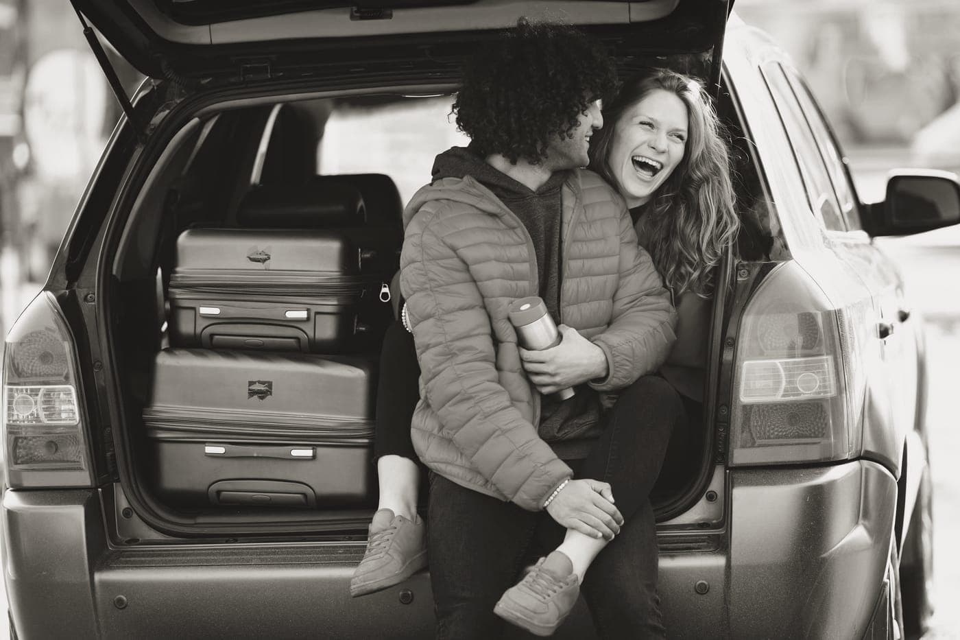 A suitcase and a duffel bag side by side beside a car
